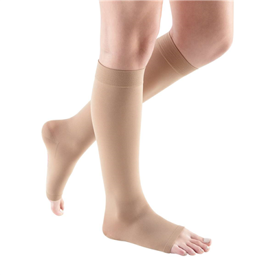 Compression knee-high sock in beige worn on lower legs, open-toe style with wide band top, calf length