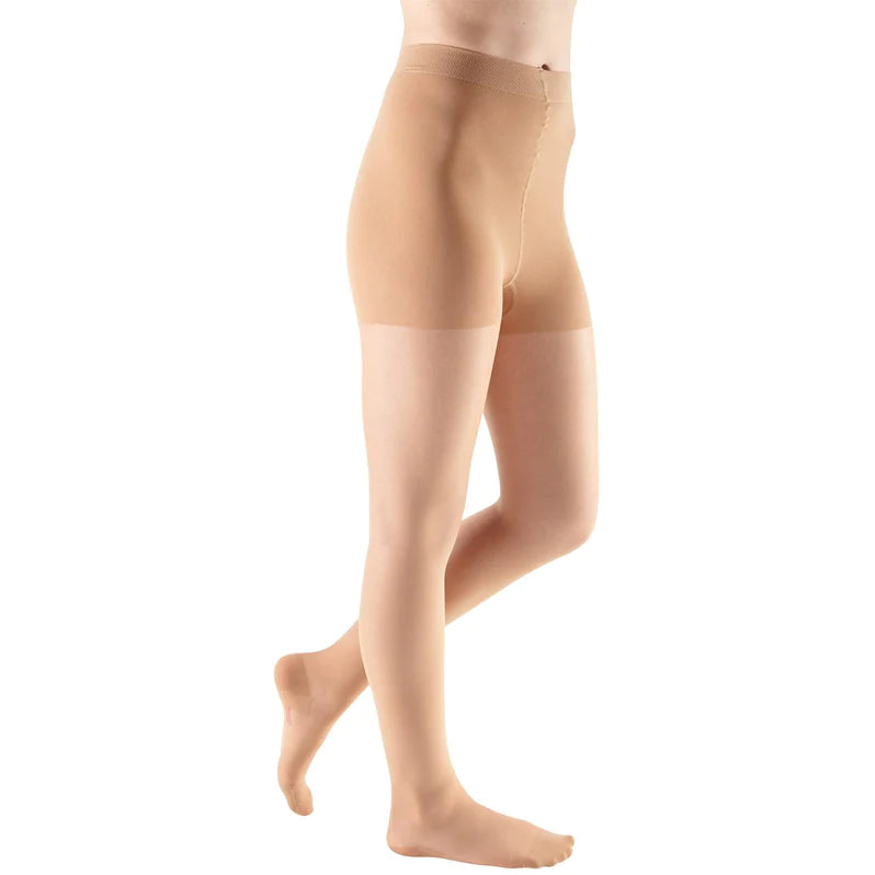Compression pantyhose in nude shown on lower body, sheer fabric with reinforced waistband, closed toe, full coverage style