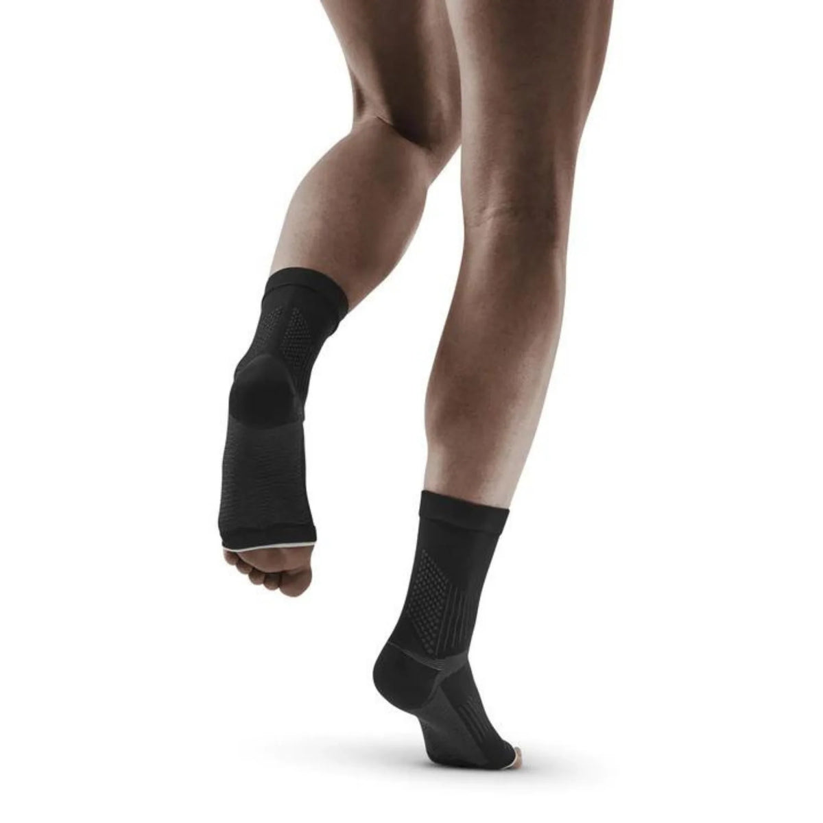 Plantar fasciitis compression sleeves in black worn on both feet, shown from behind on a person mid-stride