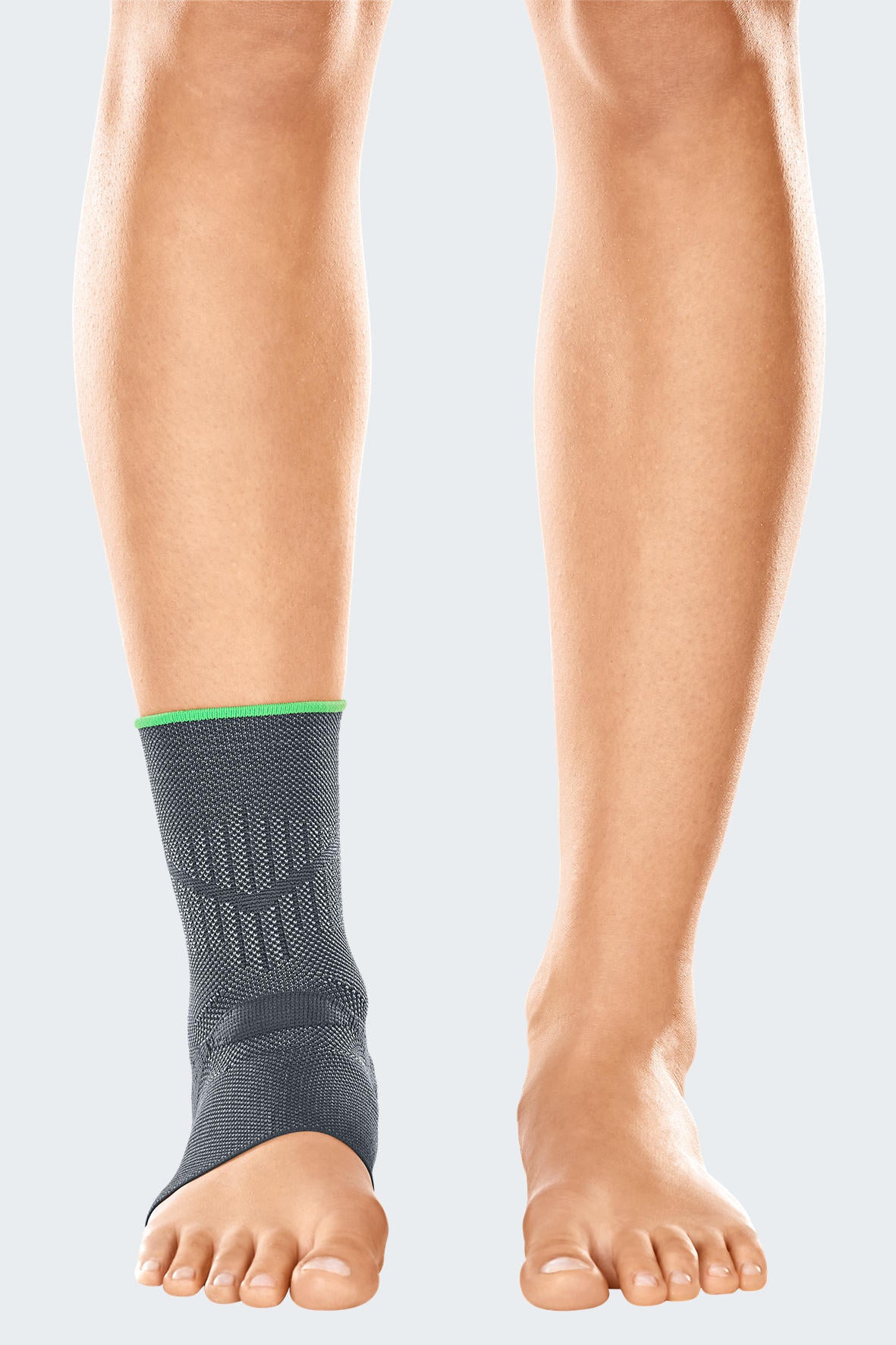Ankle support brace in gray knit fabric with green trim and structured heel pad, worn on a person's left ankle