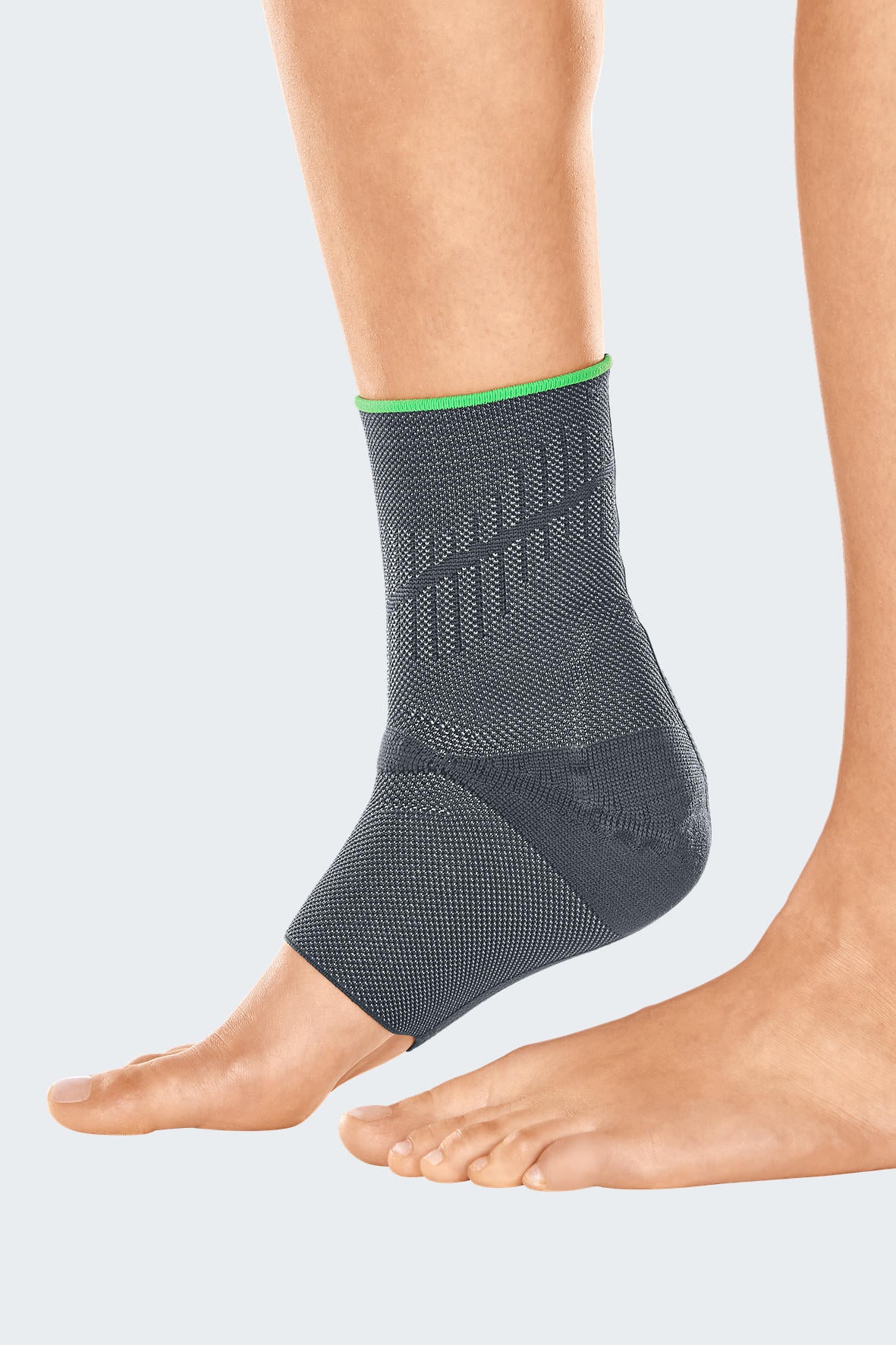 Ankle support brace in gray knit fabric with green trim and structured heel cup, worn on a bare foot and ankle