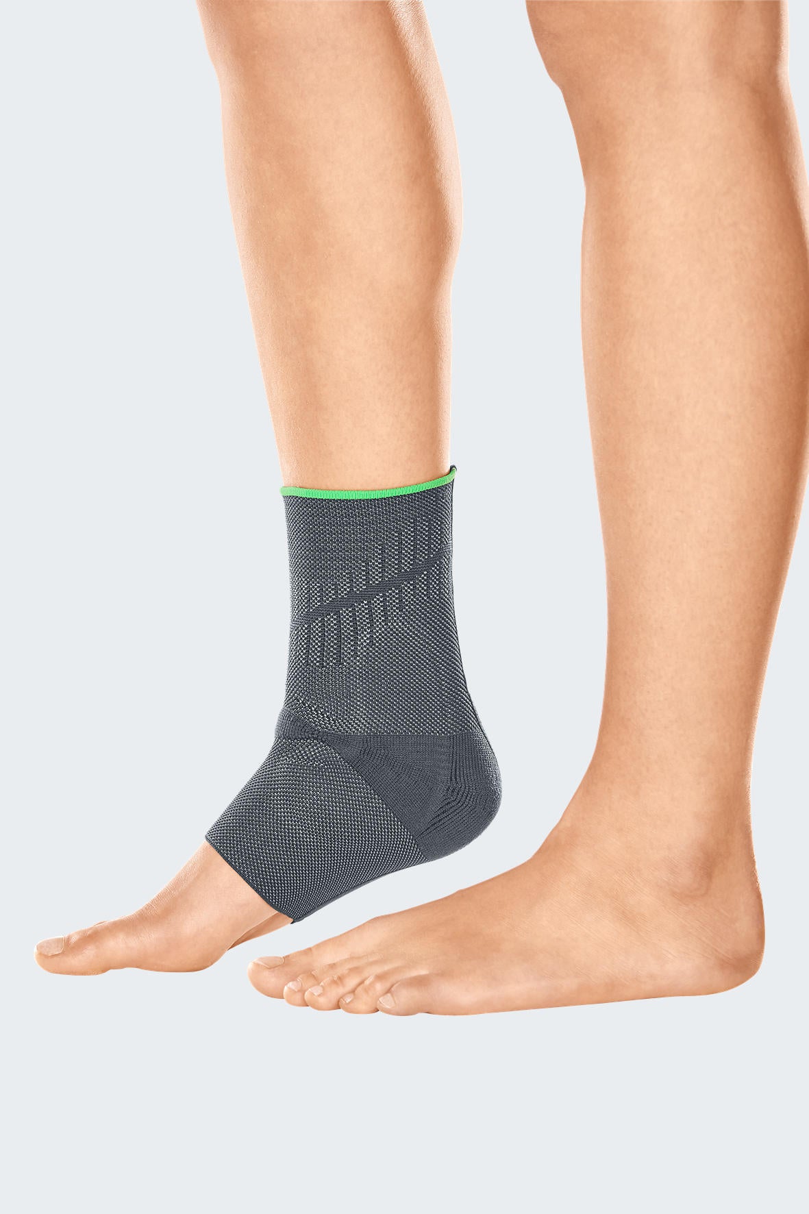 Ankle support in gray knit fabric with green trim and textured reinforcement zones, worn on a person's left ankle