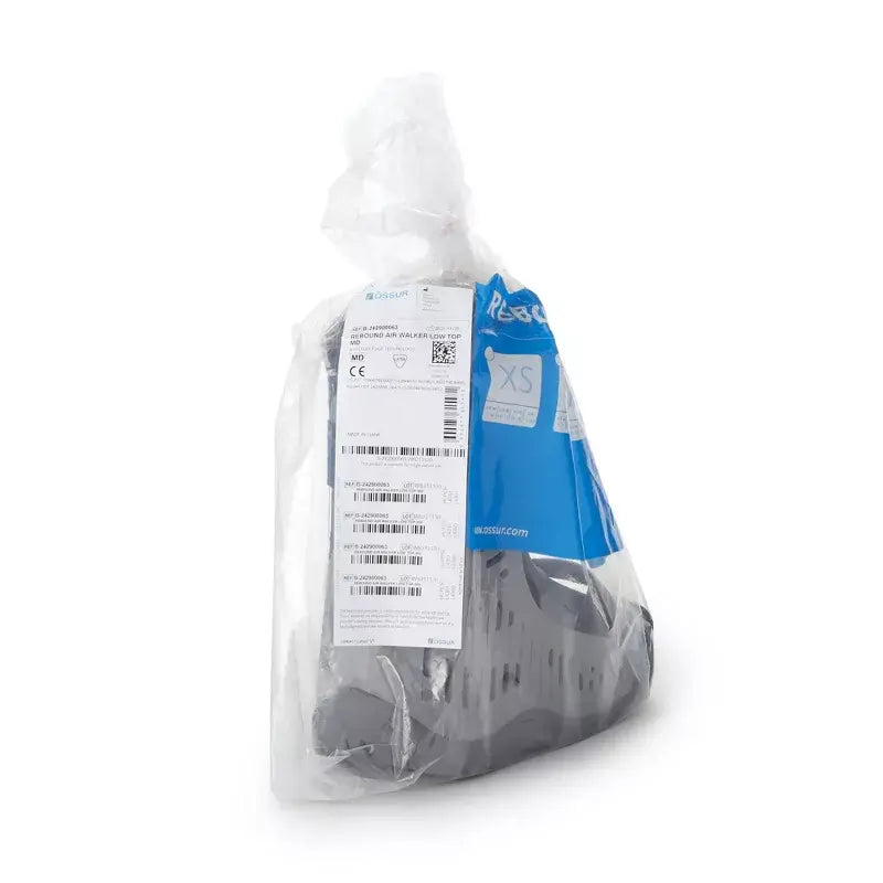 Walking boot in sealed clear plastic packaging with product label and blue size XS tag visible on white background