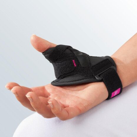 Rhizomed Soft Thumb Support in black with pink label worn on right hand, featuring wraparound straps and rigid thumb