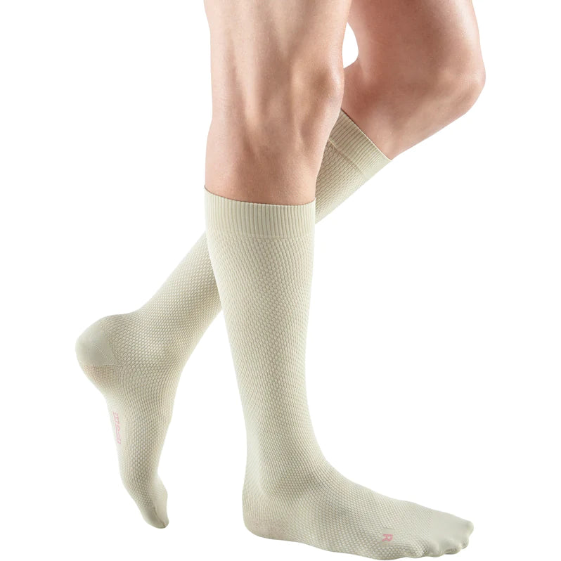 Compression socks in beige with textured knit pattern worn on a person's lower legs, knee-high closed toe style