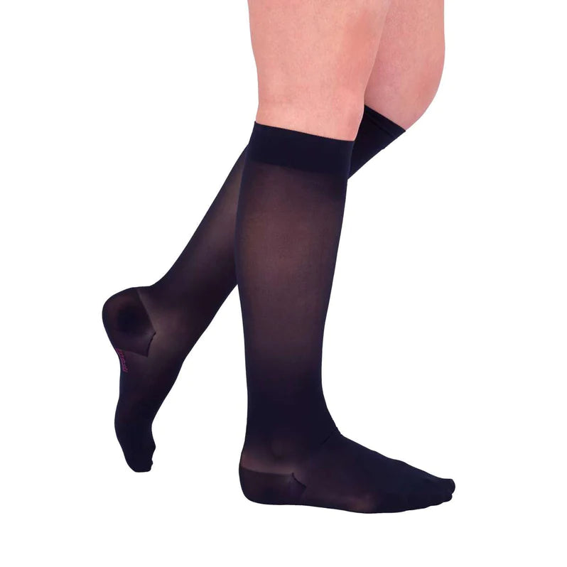 Compression knee-high stockings in sheer black worn on a woman's legs, shown from the knee down against a white background