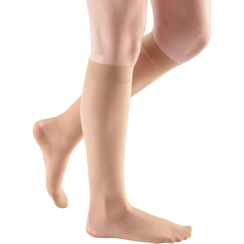 Compression knee-high stockings in beige worn on both legs, shown from knees down on white background
