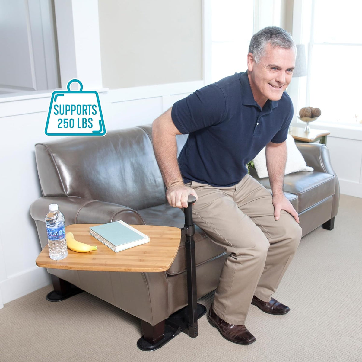 Stander Assist-A-Tray couch stand assist bar with bamboo side table, shown with man rising from gray leather sofa