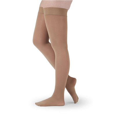 Thigh-high compression stockings in beige with silicone top band, shown on legs from hips down, closed toe style