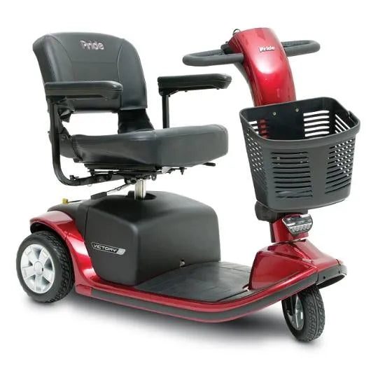 Three-wheel mobility scooter in red with black padded seat, armrests, tiller controls, and front storage basket