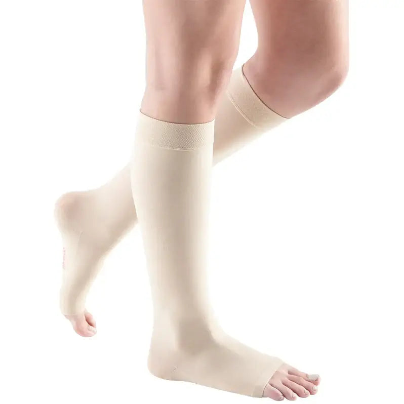 Knee-high open-toe compression stockings in beige worn on both legs, shown against a white background