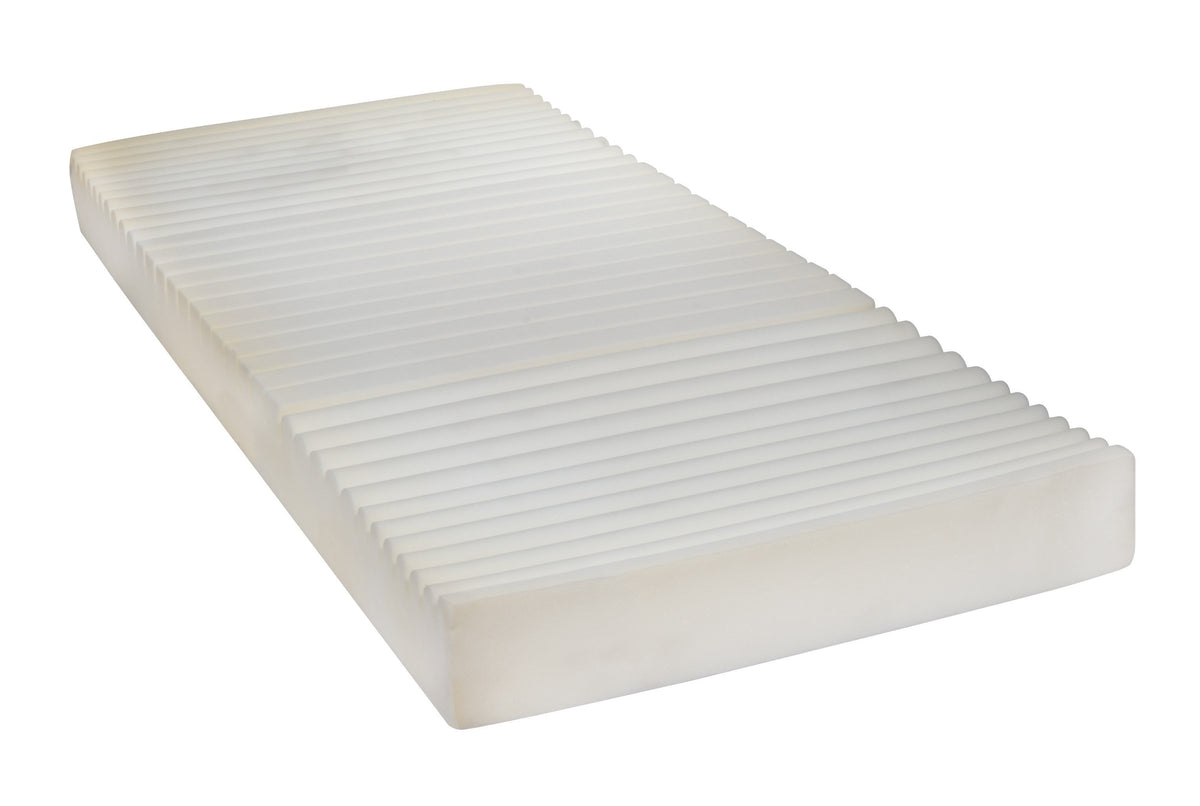 Therapeutic foam pressure reduction mattress with five-zone ribbed top surface and white cover, shown on white background