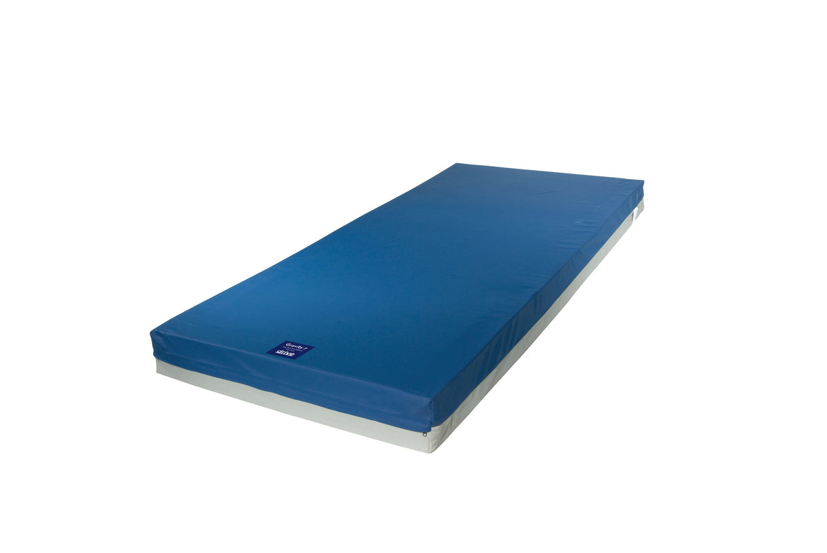 Hospital bed mattress with blue vinyl cover and gray base, shown at an angle on white background