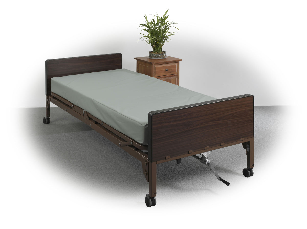 Innerspring mattress with light green cover displayed on a dark wood-finish hospital bed with casters and side rails