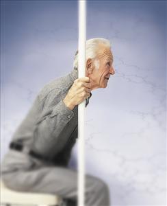 Safety pole with base, elderly man gripping white floor-to-ceiling support pole while seated, side view