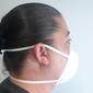N95 cup-style respirator mask with valve shown worn on a person's face, side view, white color