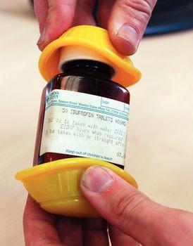 Dycem jar opener gripping a brown pill bottle being opened by hand, shown from close up