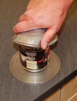 Non-slip jar opener pad on countertop with hand gripping a metal can lid