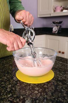 Non-slip pad in yellow under a clear mixing bowl on a countertop, with a person using a hand mixer