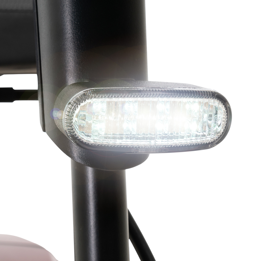 Mobility scooter LED headlight illuminated on black front fork, close-up detail view