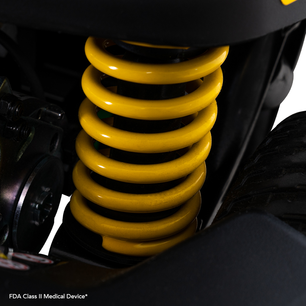 Power scooter suspension spring close-up showing yellow coil spring and black frame components