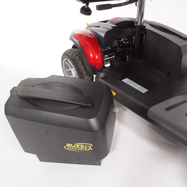 Travel scooter battery box removed from red BuzzAround EX mobility scooter, shown detached on white background