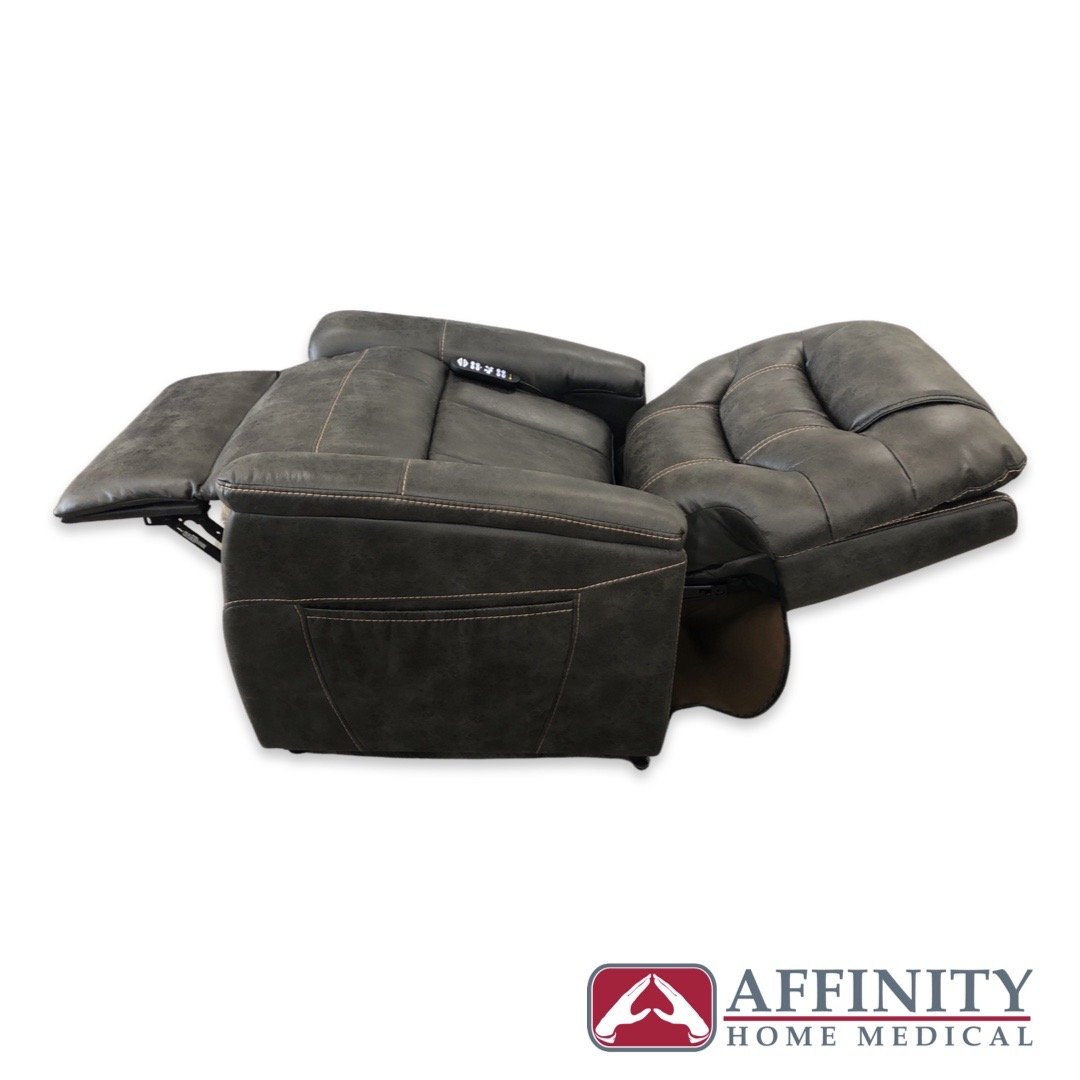 Power lift chair in dark gray upholstery shown fully reclined in flat position with footrest extended and control panel on