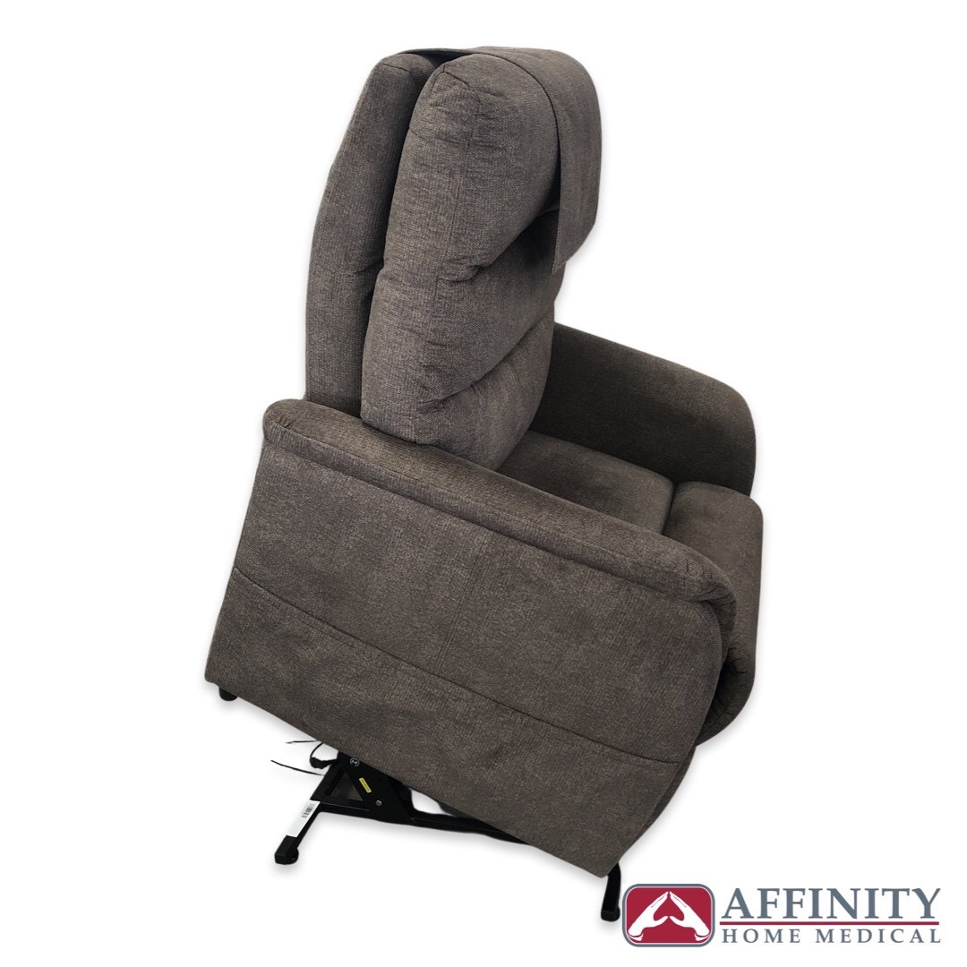Power lift chair in gray fabric shown from the side in the raised lift position with padded back and armrests on a white