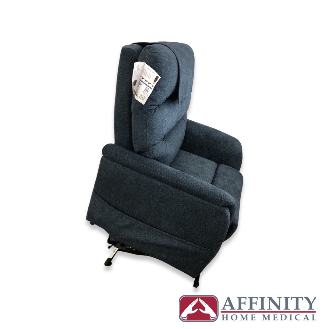 Power lift recliner chair in dark blue fabric shown in partially reclined position with tufted back, viewed from the side