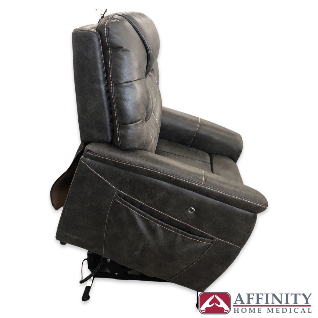 Power lift recliner chair in gray upholstery with contrast stitching, shown from the side in upright position with footrest