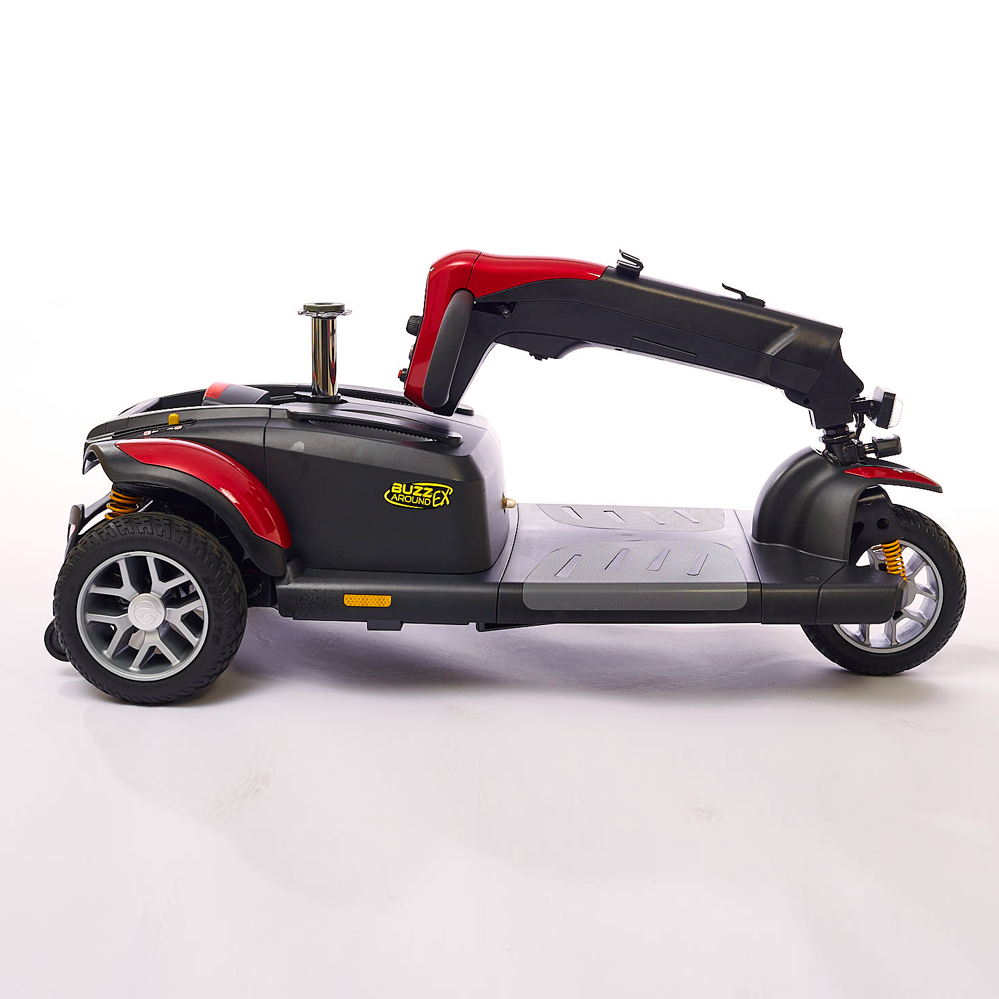 Travel scooter in red and black shown disassembled from side view, with tiller folded flat onto the base and seat removed