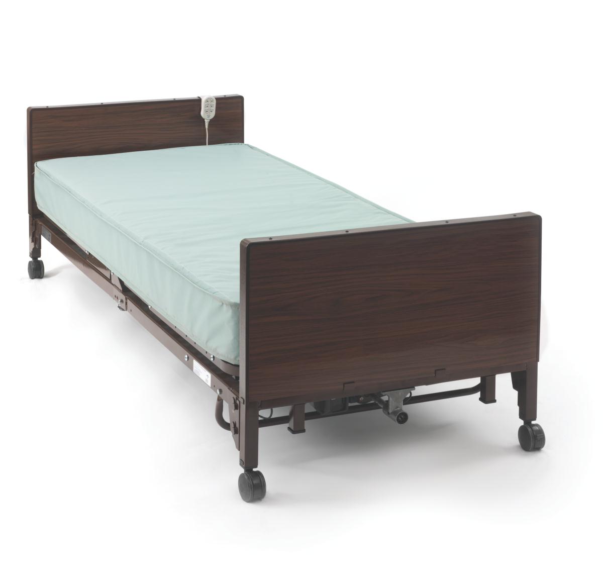 Full electric hospital bed with dark wood-finish panels, light blue mattress, wired remote control, and caster wheels on