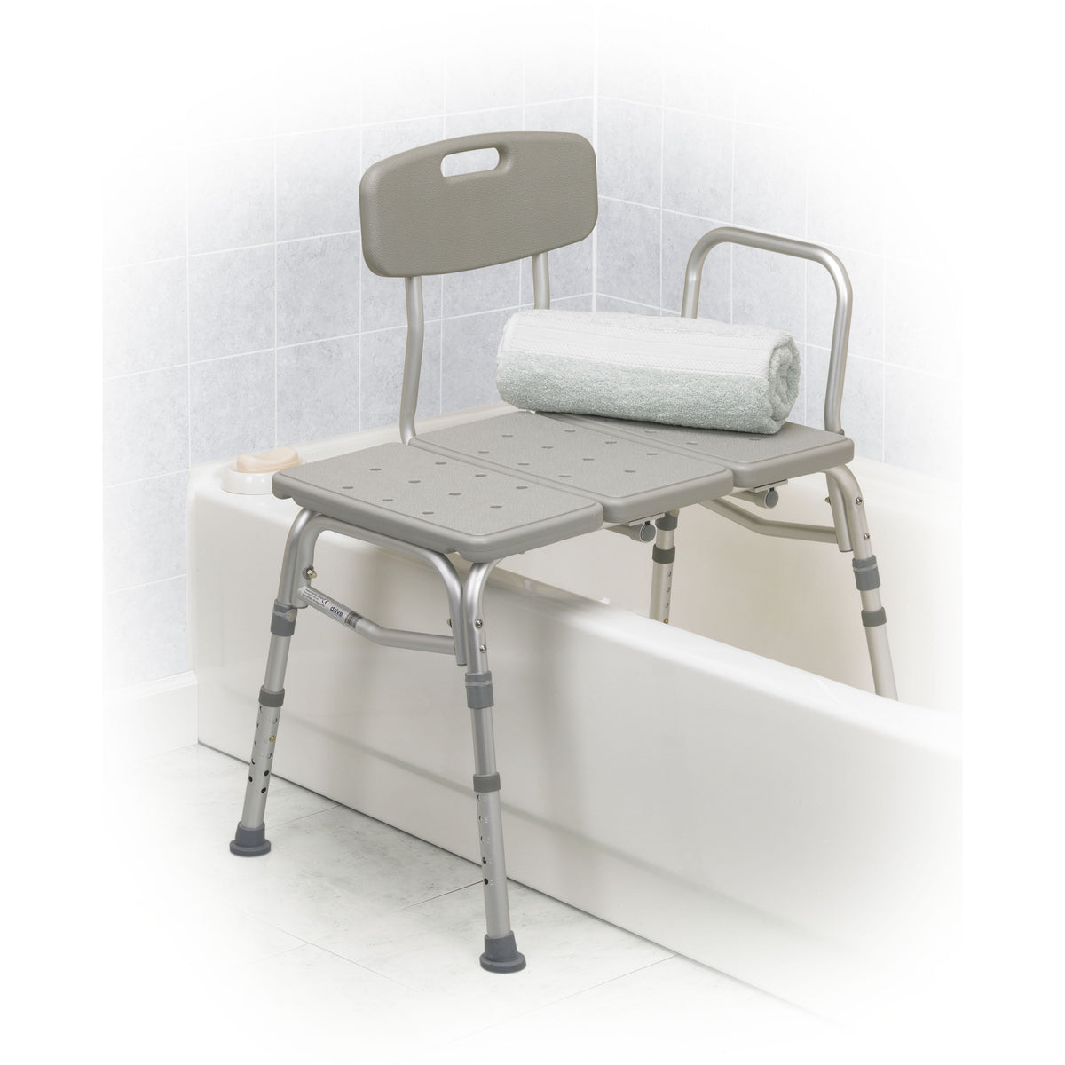 Transfer bench with gray plastic seat, backrest, and armrest spanning a white bathtub, with a rolled white towel on the seat