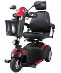 Three-wheel mobility scooter in red and black with captain's seat, armrests, tiller, and front basket